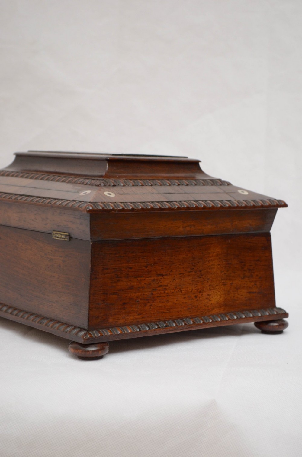 An open dark wood sarcophagus-shaped jewellery box featuring a mother-of-pearl escutcheon and a removable tray lined with floral paper. View II