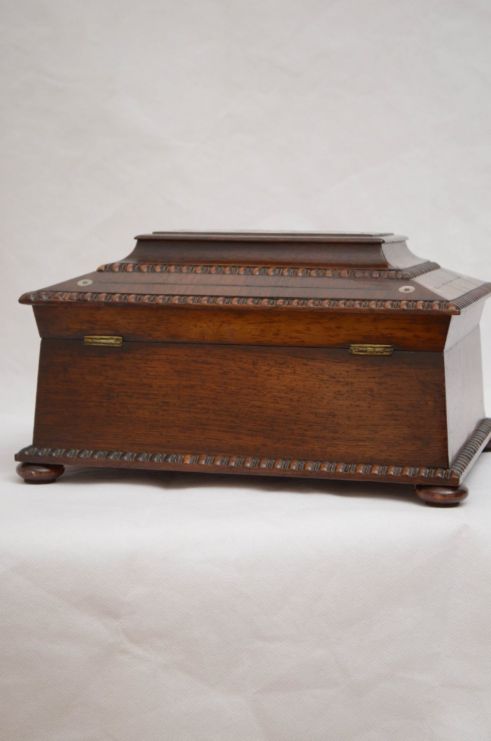 An open dark wood sarcophagus-shaped jewellery box featuring a mother-of-pearl escutcheon and a removable tray lined with floral paper. View XV