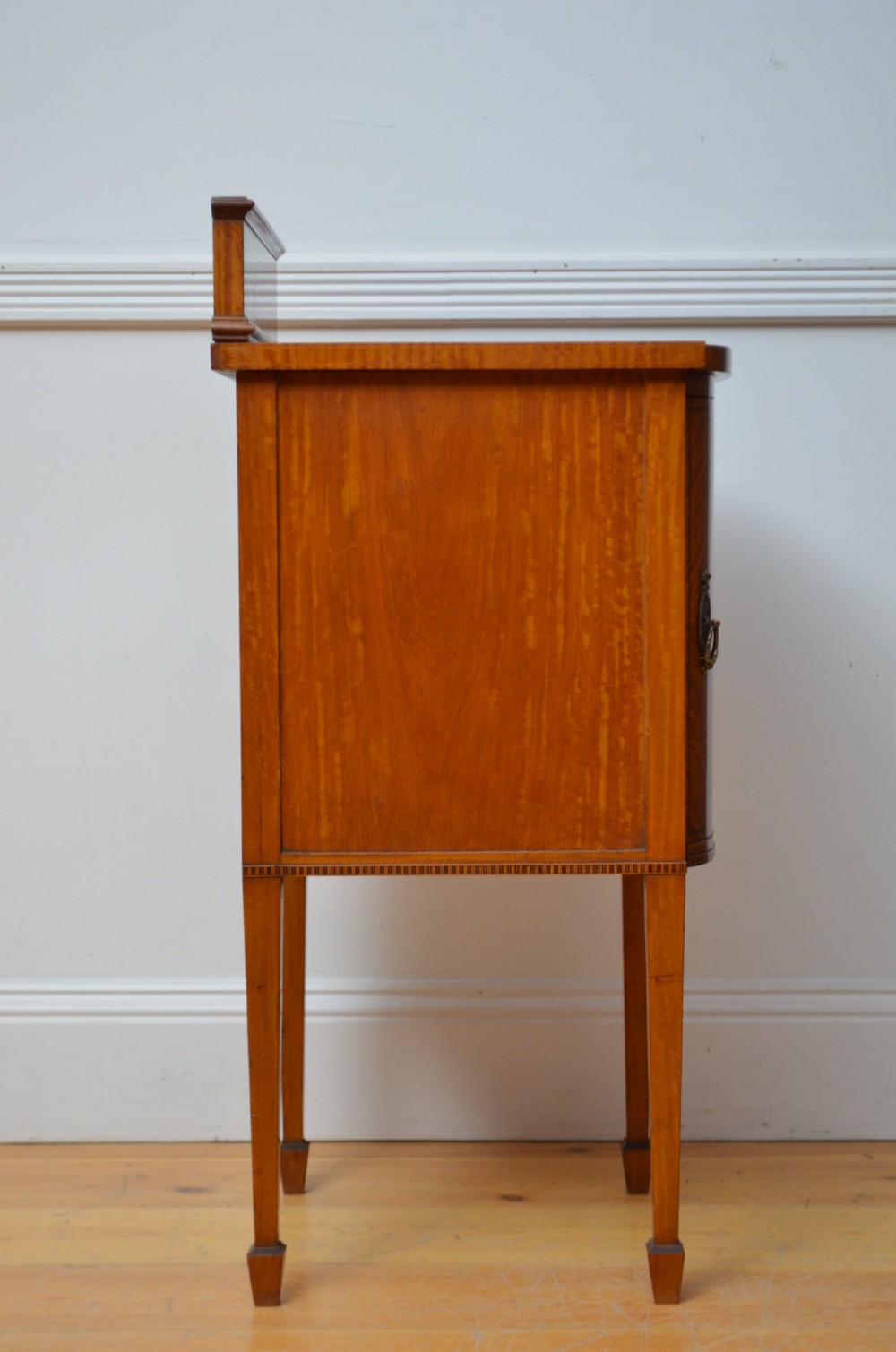 An Edwardian satinwood bedside cabinet with a gallery upstand top, diamond-patterned veneered cupboard door, and square tapered legs. View XI