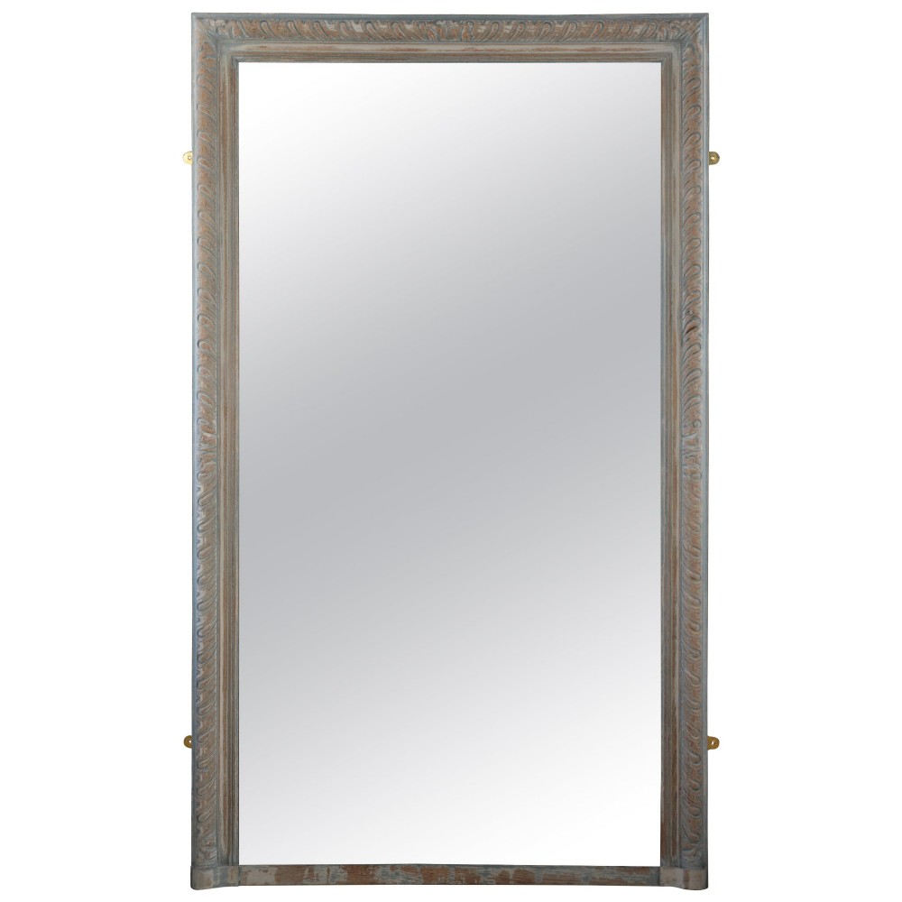A tall rectangular wall or floor mirror featuring a relief-carved oak frame with a grey-washed finish and brass side brackets.