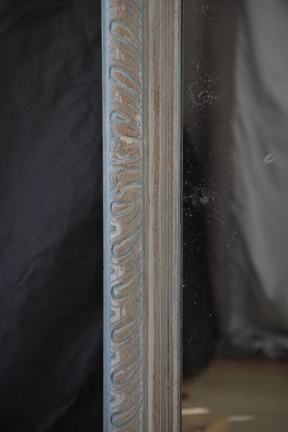 A tall rectangular wall or floor mirror featuring a relief-carved oak frame with a grey-washed finish and brass side brackets. View IV