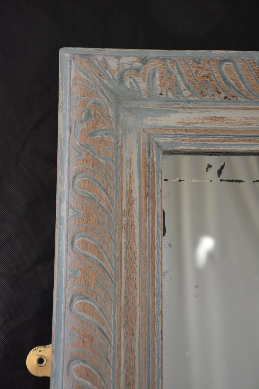A tall rectangular wall or floor mirror featuring a relief-carved oak frame with a grey-washed finish and brass side brackets. View V
