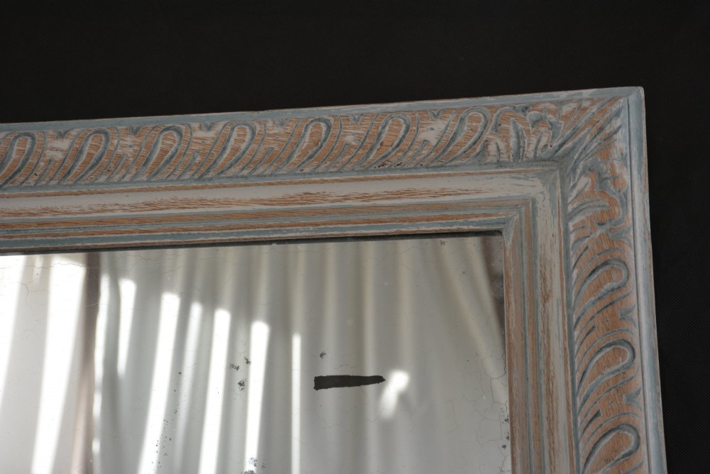 A tall rectangular wall or floor mirror featuring a relief-carved oak frame with a grey-washed finish and brass side brackets. View VI
