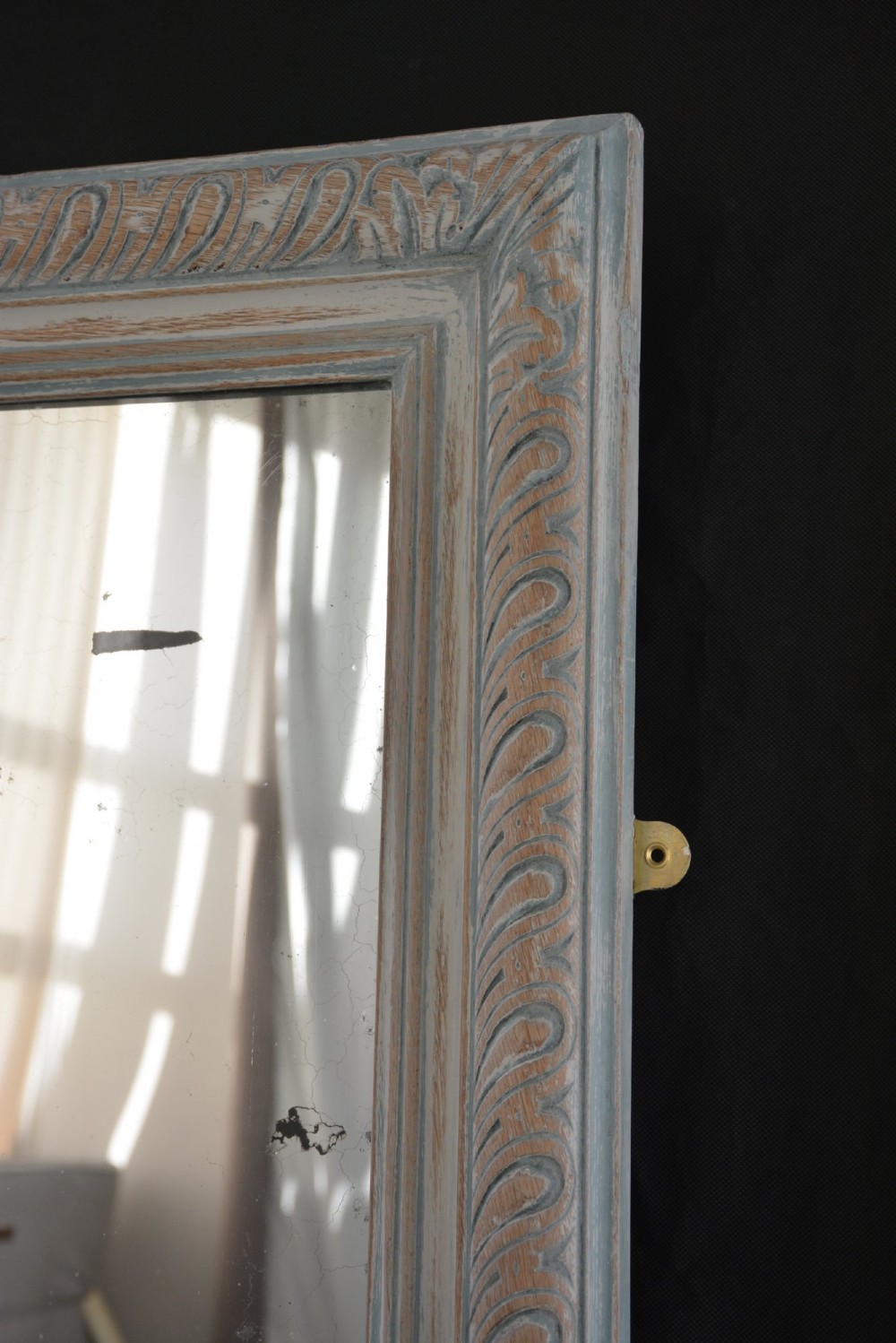A tall rectangular wall or floor mirror featuring a relief-carved oak frame with a grey-washed finish and brass side brackets. View VII