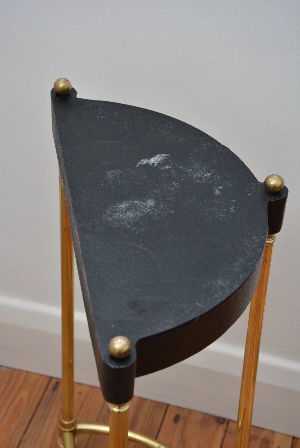 A semi-circular brass umbrella stand featuring finial tops, vertical tubular legs, a partitioned top frame, and a black drip tray base. View II