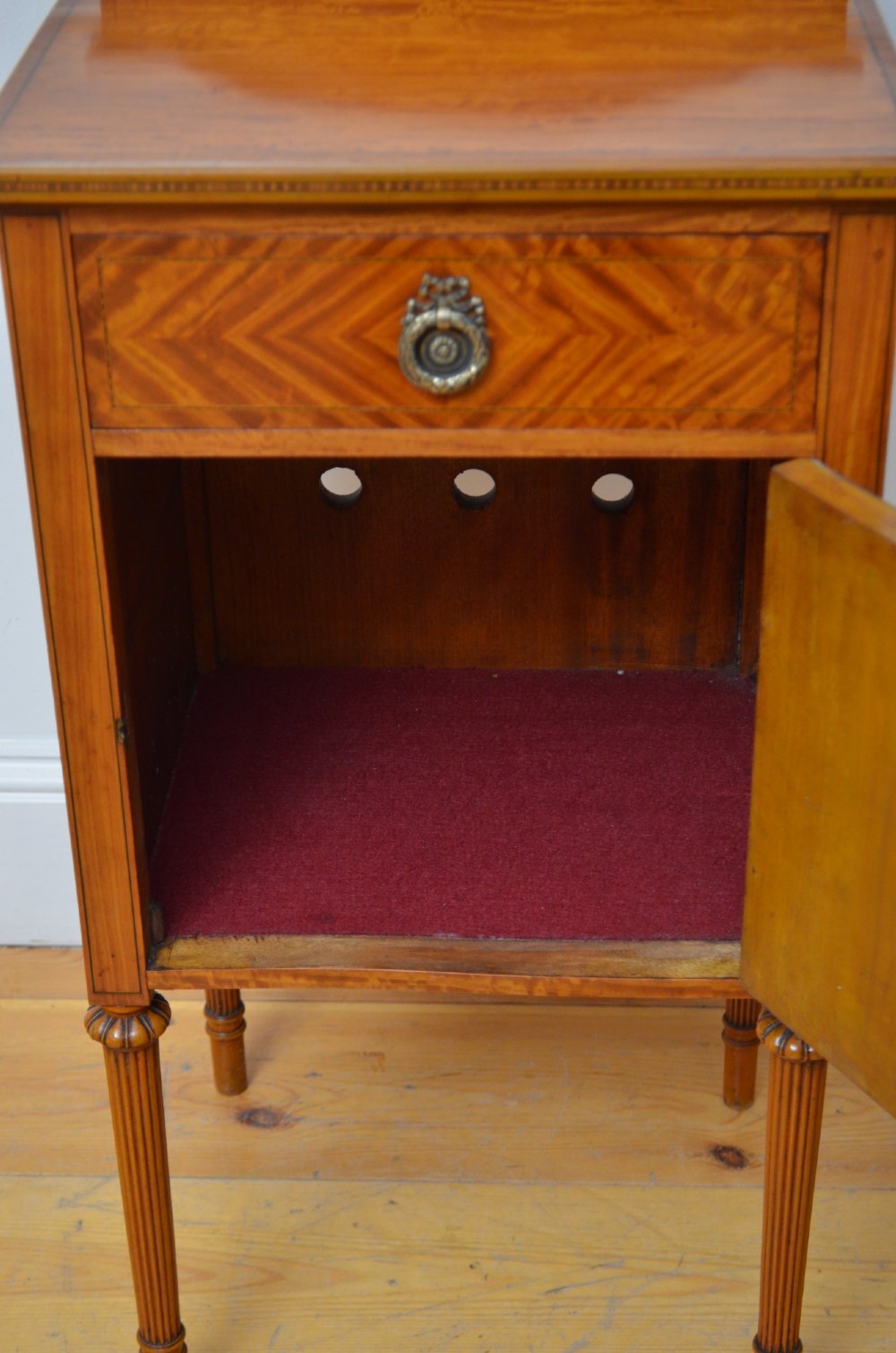 An Edwardian satinwood bedside cupboard featuring chevron veneer detailing, an upper drawer, a lower door, and turned reeded legs. View VI