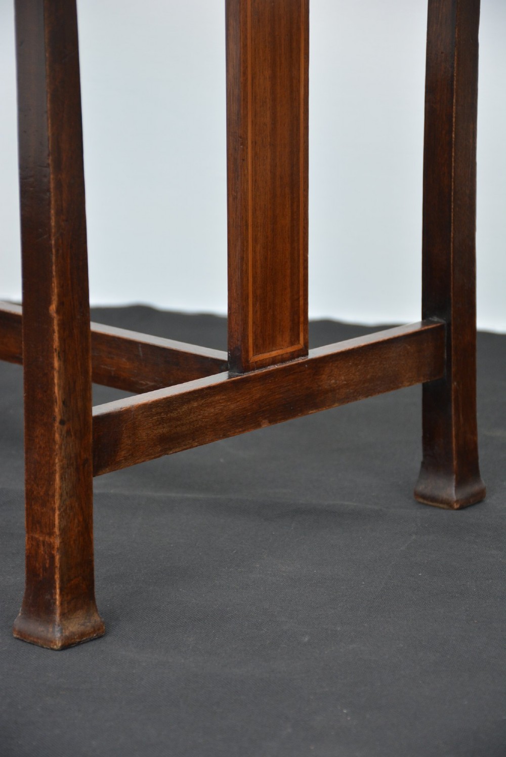An antique dark mahogany Arts and Crafts stool featuring upright corner posts with square finials, vertical side splats, and a pattern-upholstered fabric seat. View VI