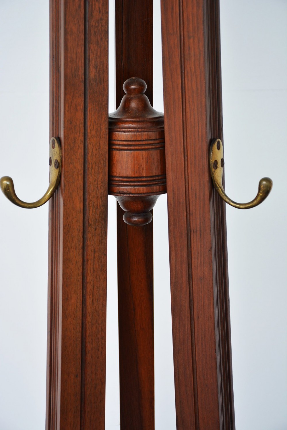 A tall freestanding dark walnut coat stand featuring a slatted central column, brass hooks, a turned finial, and four splayed feet. View XI