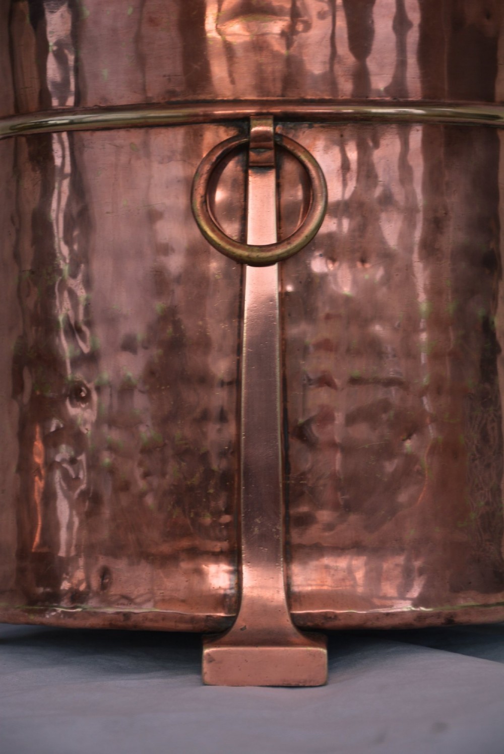 An Arts and Crafts hammered copper cylindrical coal bin featuring a fitted lid, drop side ring handles, structural legs, and a removable metal liner. View IX