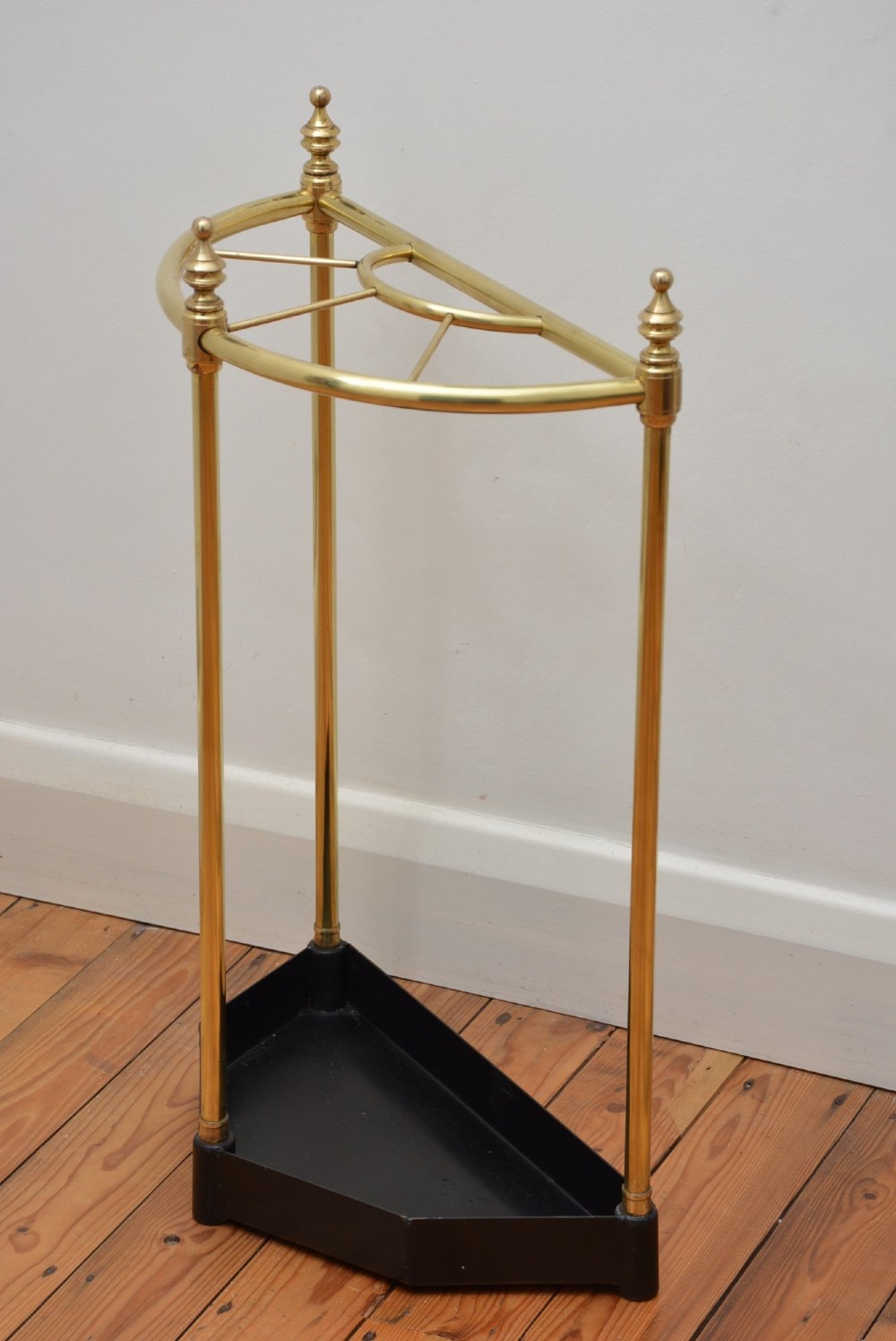 A brass demi-lune umbrella stand featuring three vertical posts topped with turned finials, internal division bars, and a black metal drip tray base. View II