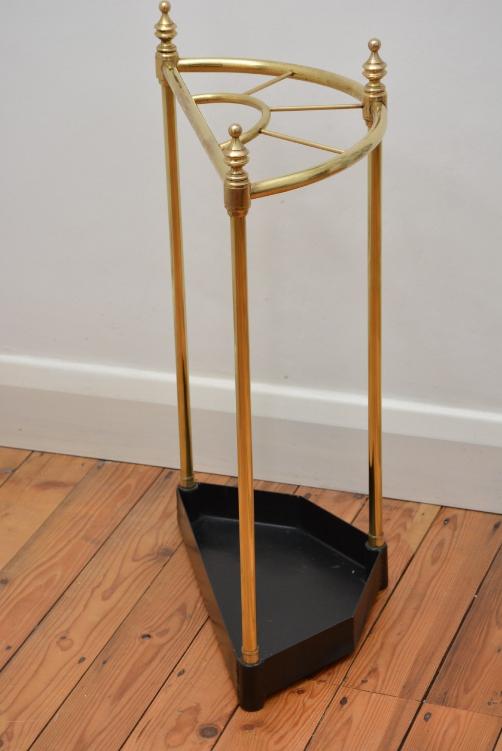 A brass demi-lune umbrella stand featuring three vertical posts topped with turned finials, internal division bars, and a black metal drip tray base. View III