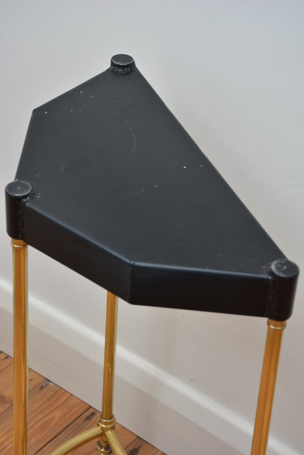 A brass demi-lune umbrella stand featuring three vertical posts topped with turned finials, internal division bars, and a black metal drip tray base. View X