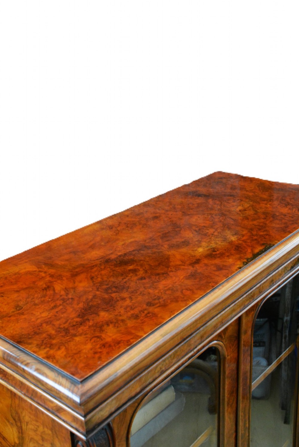 An English Victorian low bookcase made of figured walnut with two arched glass doors, carved corbels, and internal shelves. View VI