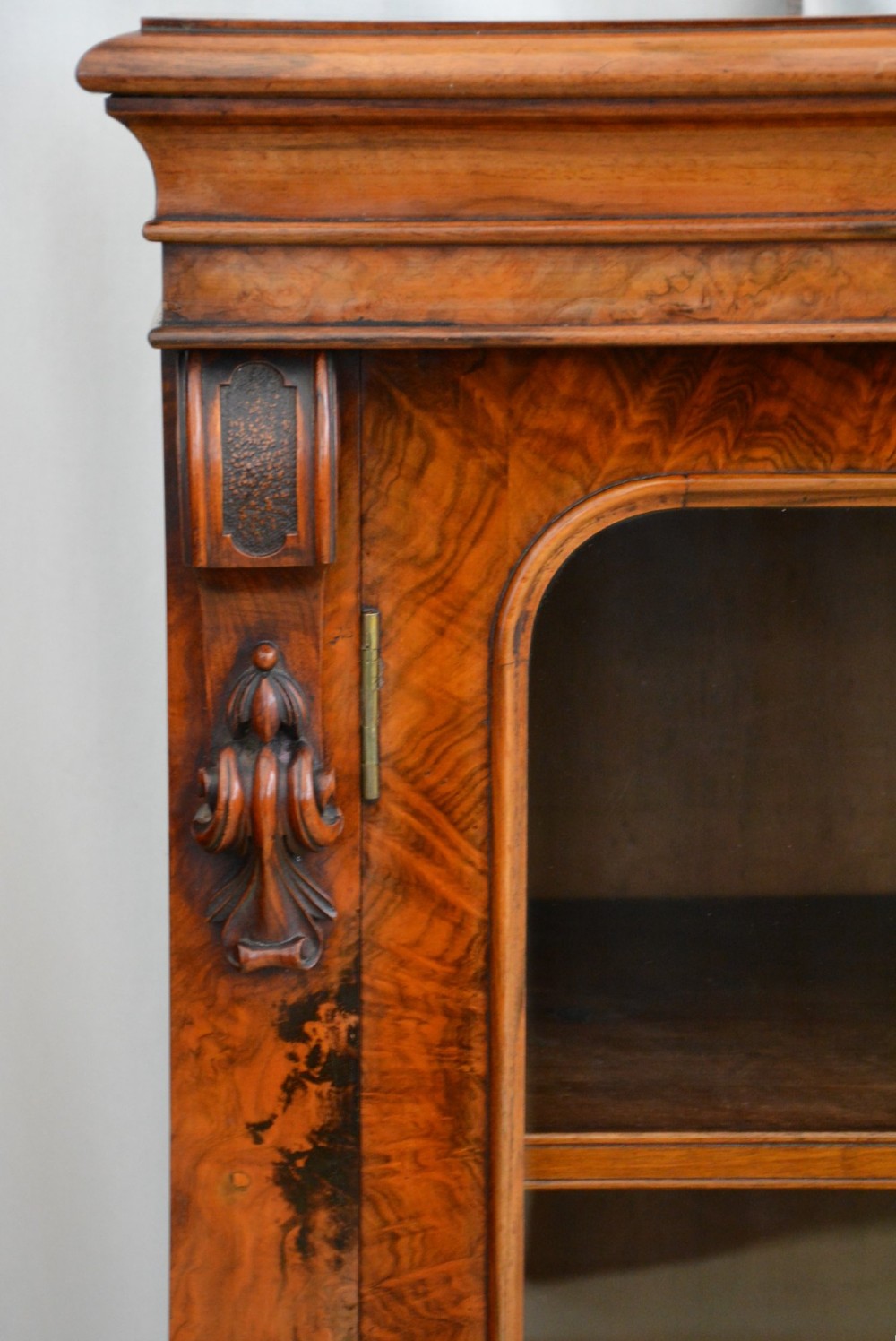 An English Victorian low bookcase made of figured walnut with two arched glass doors, carved corbels, and internal shelves. View VIII