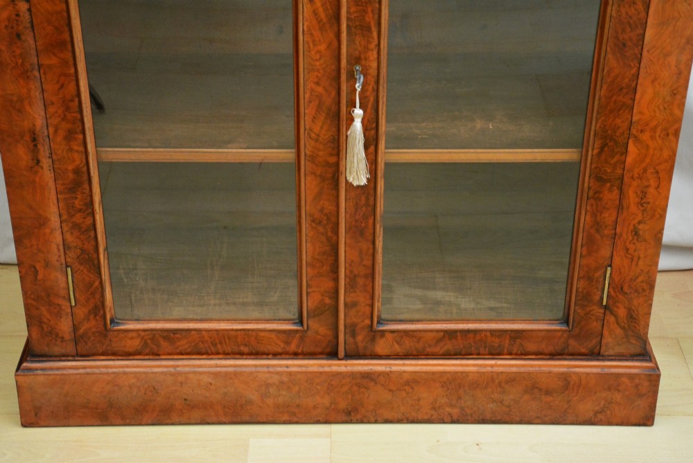An English Victorian low bookcase made of figured walnut with two arched glass doors, carved corbels, and internal shelves. View XII