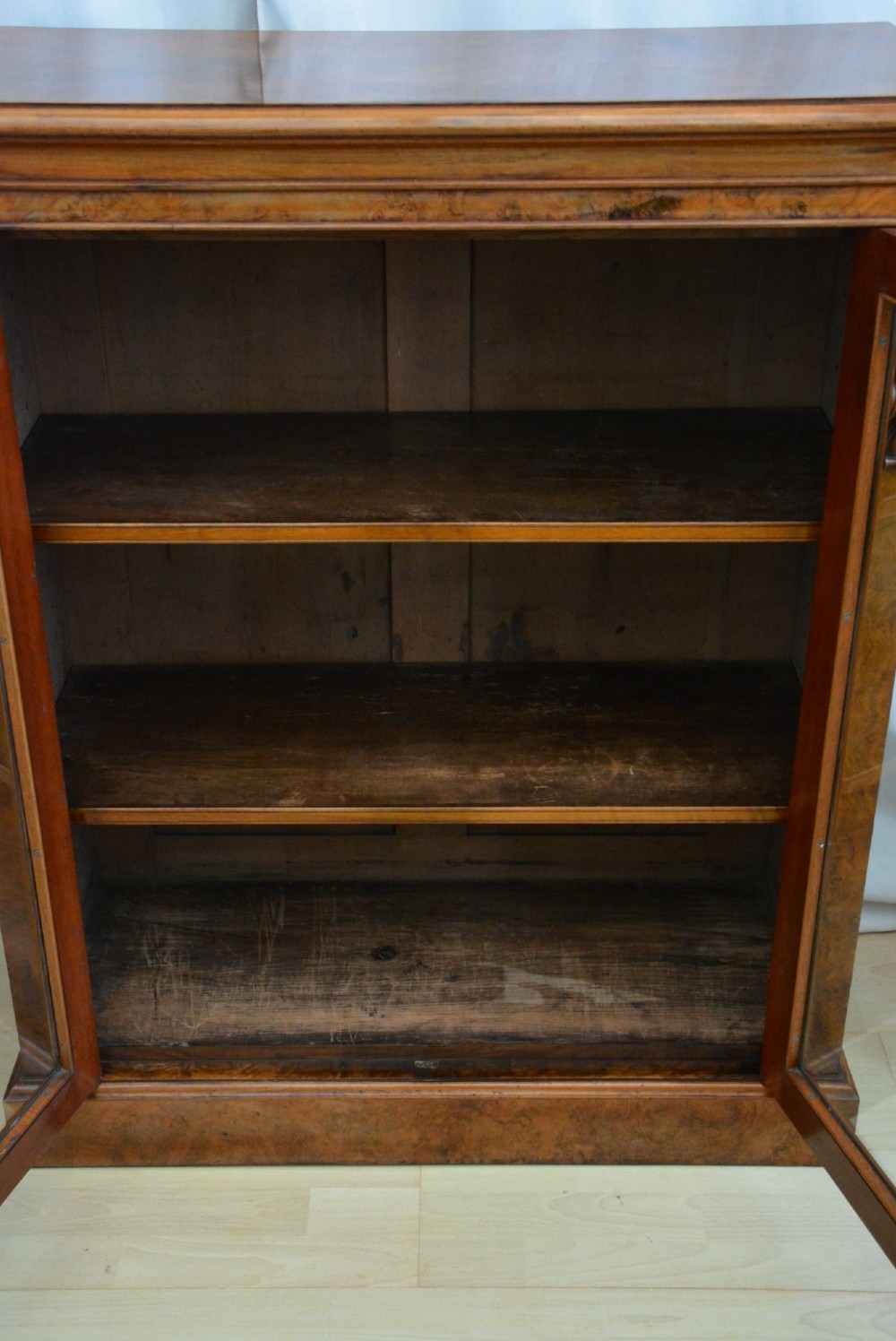 An English Victorian low bookcase made of figured walnut with two arched glass doors, carved corbels, and internal shelves. View XIII
