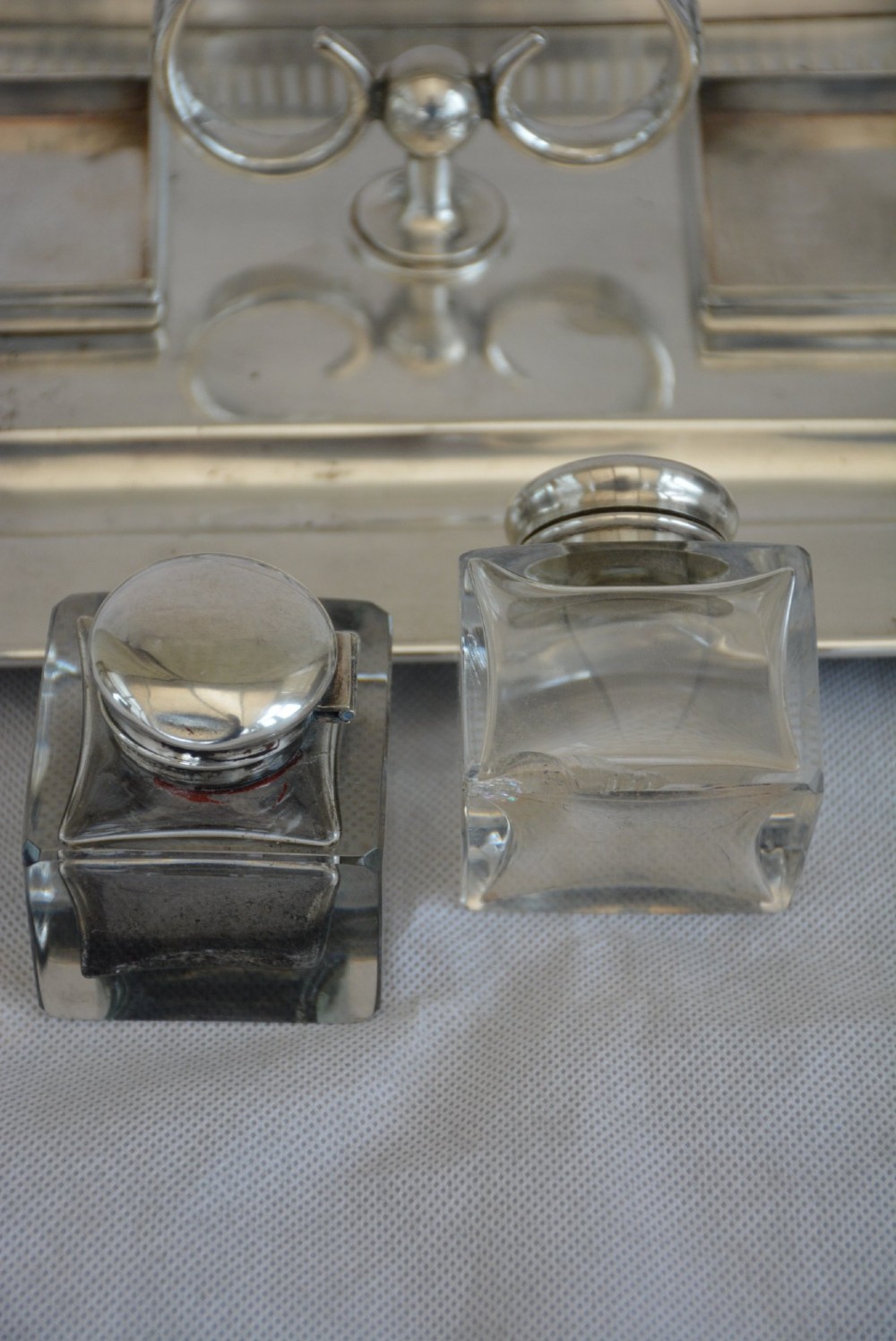 A rectangular silver-plated inkstand featuring a pierced gallery, central handle, built-in pen groove, and two clear glass inkwells with silver lids resting on ball feet. View XIV