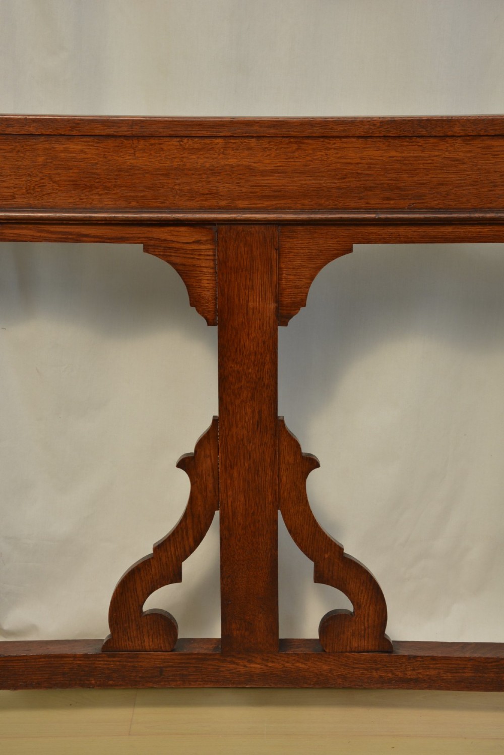 A tall Victorian Gothic oak hall stand featuring cross-braced lattice framing, metal coat pegs, finial tops, and carved architectural supports. View II
