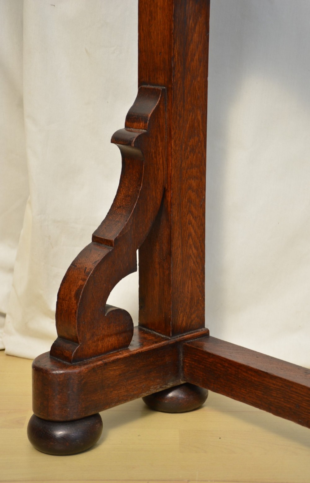 A tall Victorian Gothic oak hall stand featuring cross-braced lattice framing, metal coat pegs, finial tops, and carved architectural supports. View III