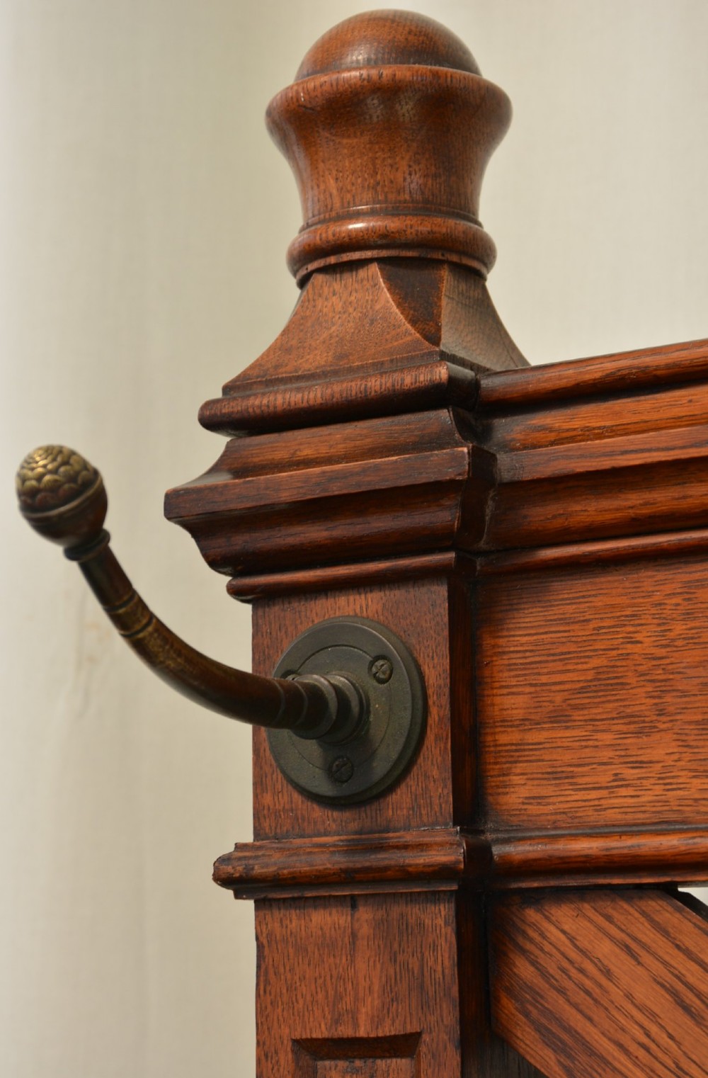 A tall Victorian Gothic oak hall stand featuring cross-braced lattice framing, metal coat pegs, finial tops, and carved architectural supports. View VII