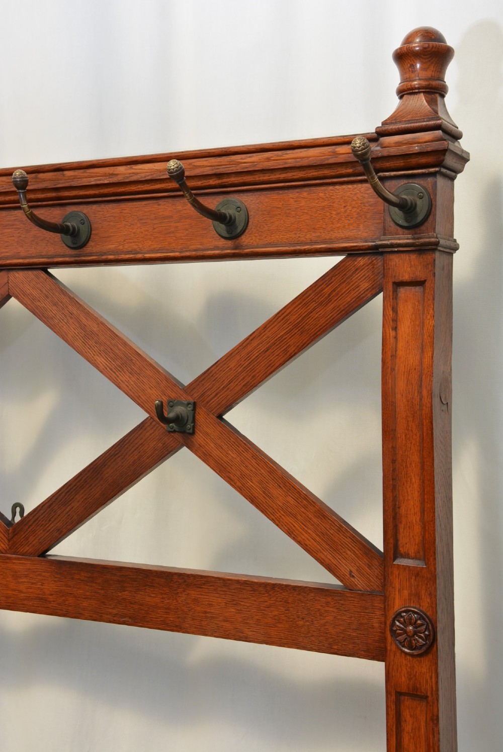 A tall Victorian Gothic oak hall stand featuring cross-braced lattice framing, metal coat pegs, finial tops, and carved architectural supports. View IX