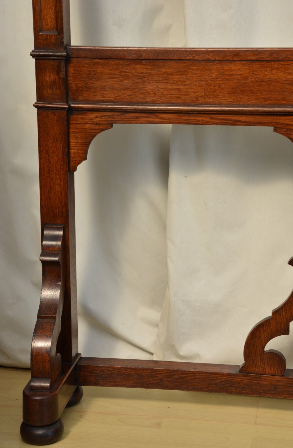 A tall Victorian Gothic oak hall stand featuring cross-braced lattice framing, metal coat pegs, finial tops, and carved architectural supports. View XV