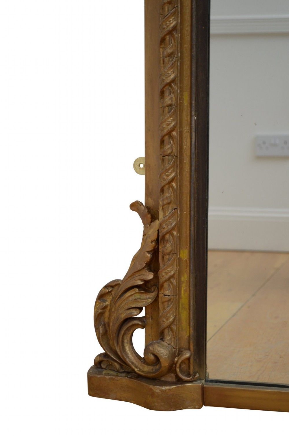 A tall arched overmantel mirror featuring a gold gilded frame decorated with an intricate carved top cresting and scroll base feet. View II