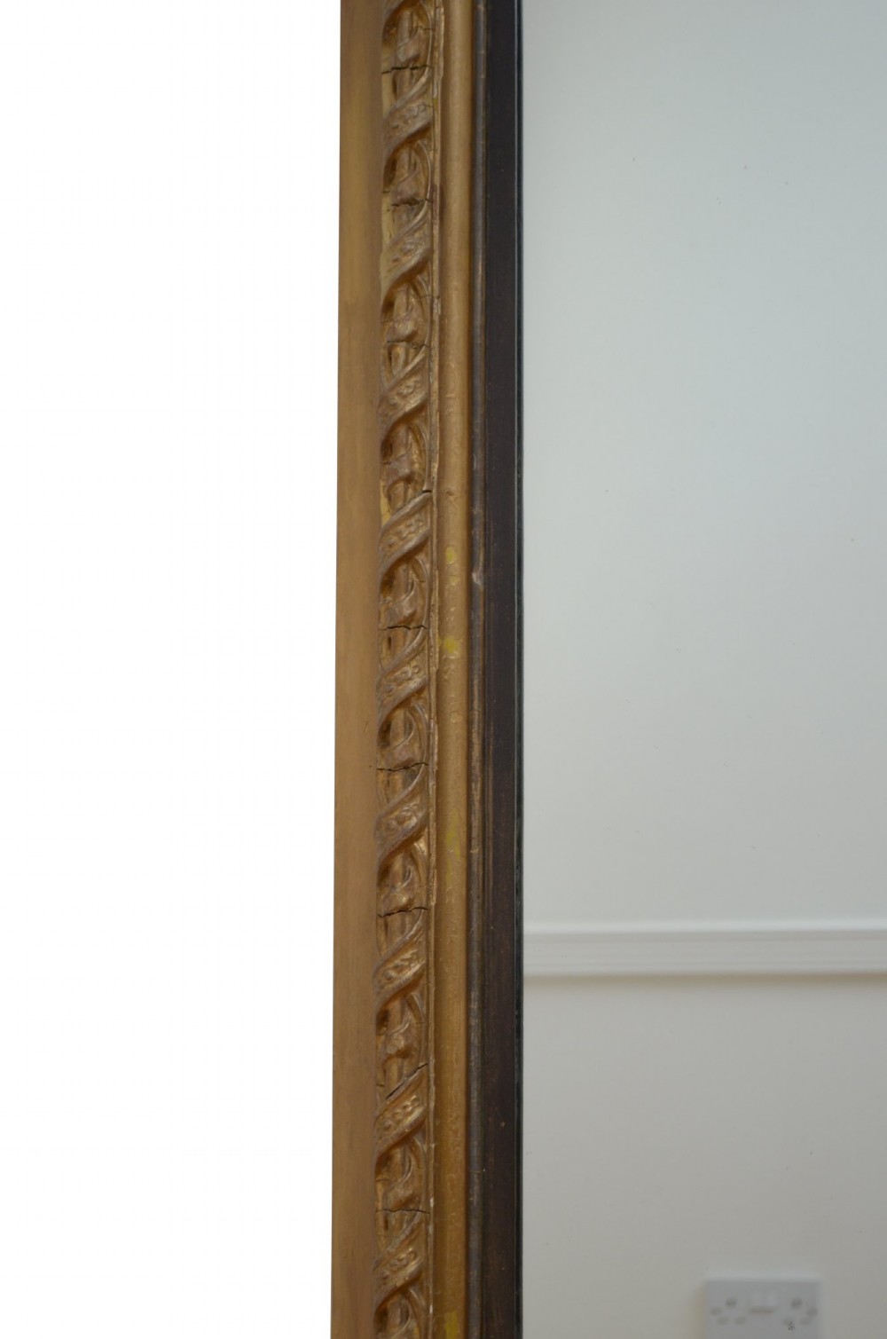 A tall arched overmantel mirror featuring a gold gilded frame decorated with an intricate carved top cresting and scroll base feet. View III