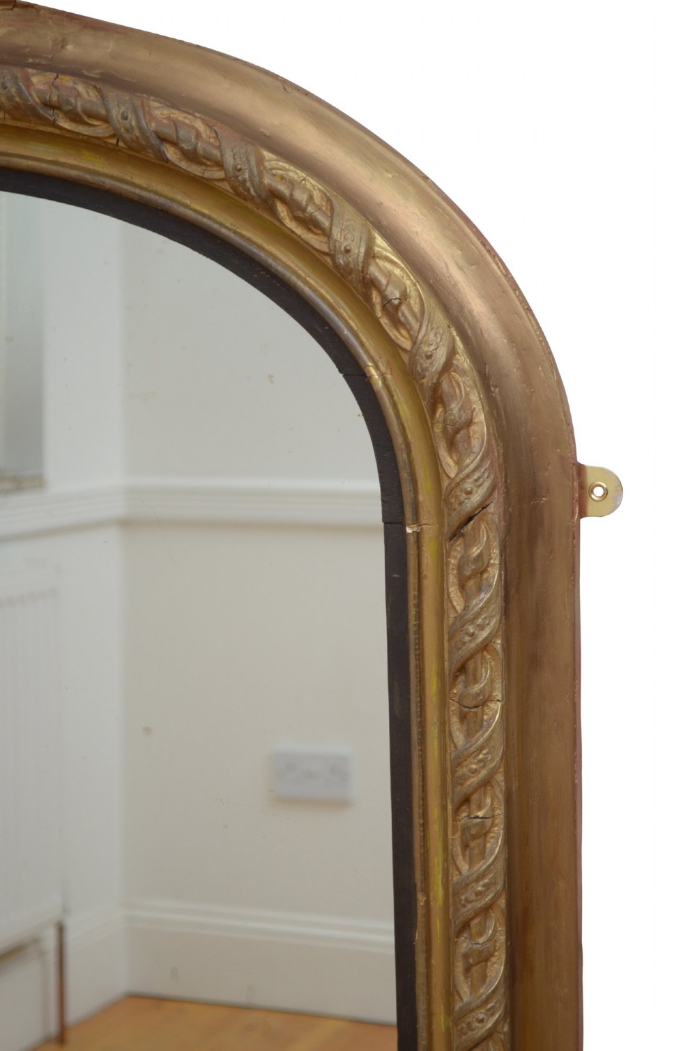 A tall arched overmantel mirror featuring a gold gilded frame decorated with an intricate carved top cresting and scroll base feet. View VII