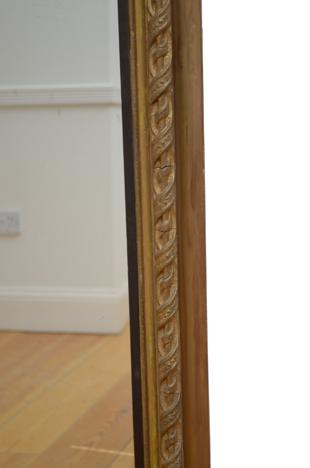 A tall arched overmantel mirror featuring a gold gilded frame decorated with an intricate carved top cresting and scroll base feet. View VIII