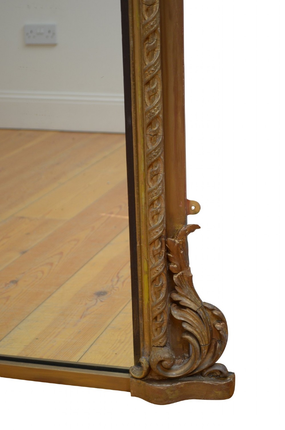 A tall arched overmantel mirror featuring a gold gilded frame decorated with an intricate carved top cresting and scroll base feet. View IX