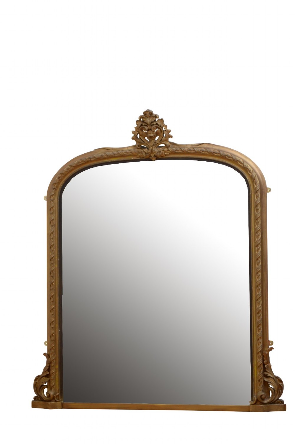 A tall arched overmantel mirror featuring a gold gilded frame decorated with an intricate carved top cresting and scroll base feet.