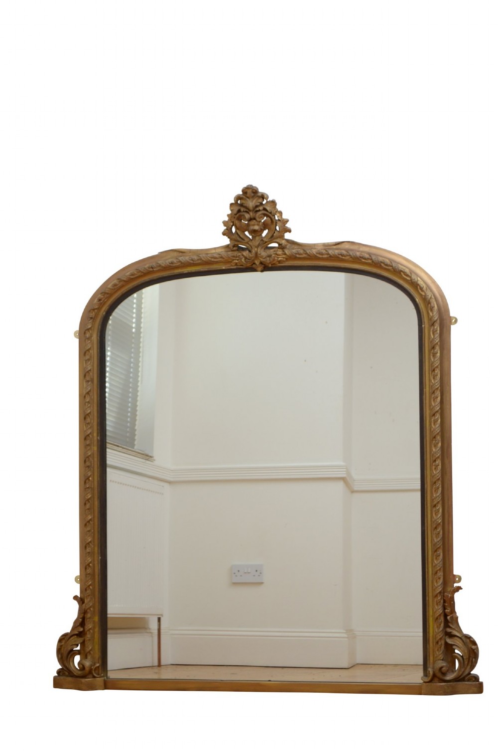 A tall arched overmantel mirror featuring a gold gilded frame decorated with an intricate carved top cresting and scroll base feet. View XI