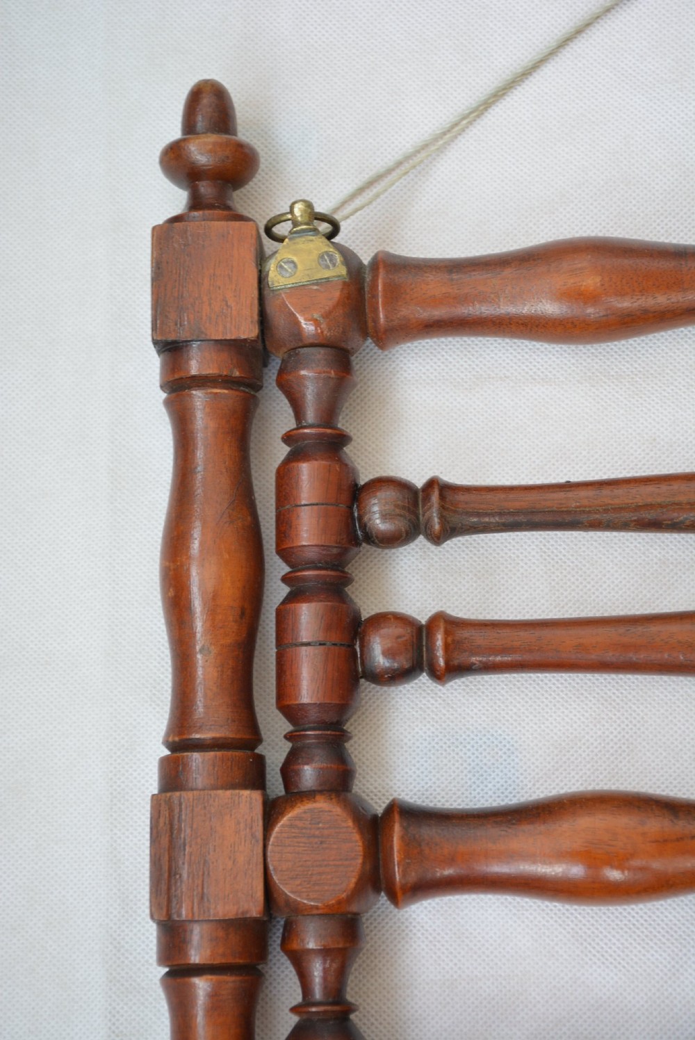 A wall-mounted dark wood coat rack constructed from turned spindles with multiple hanging pegs and decorative corner finials. View IV