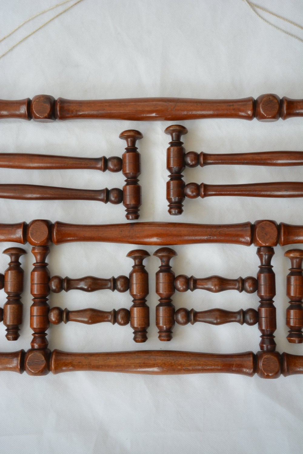 A wall-mounted dark wood coat rack constructed from turned spindles with multiple hanging pegs and decorative corner finials. View VIII