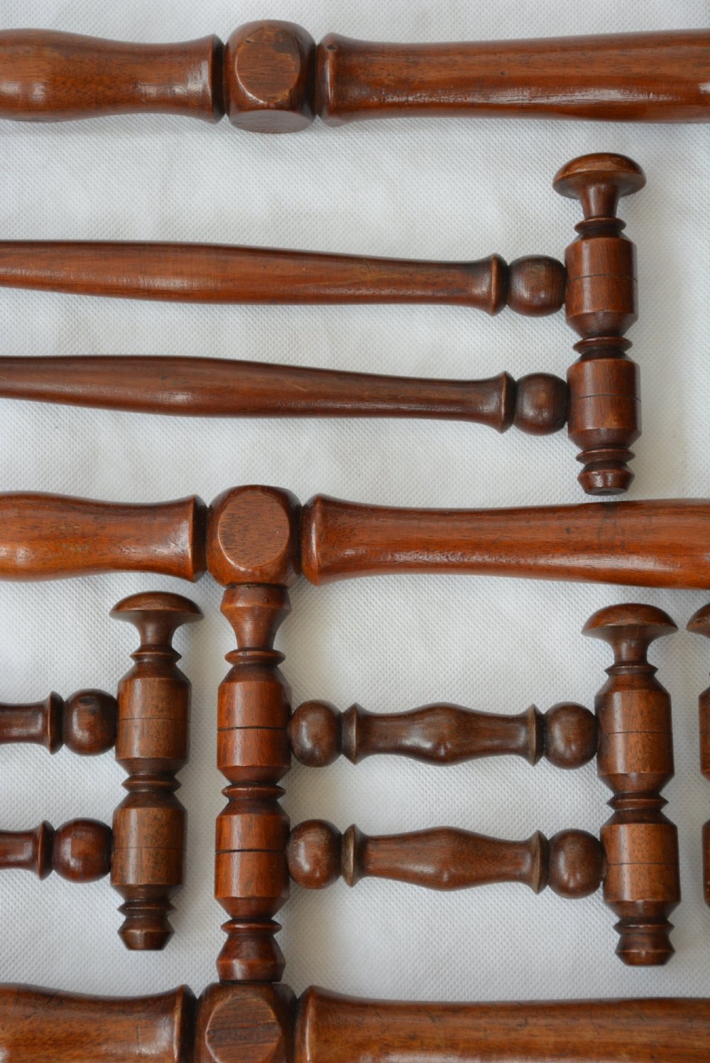 A wall-mounted dark wood coat rack constructed from turned spindles with multiple hanging pegs and decorative corner finials. View XI
