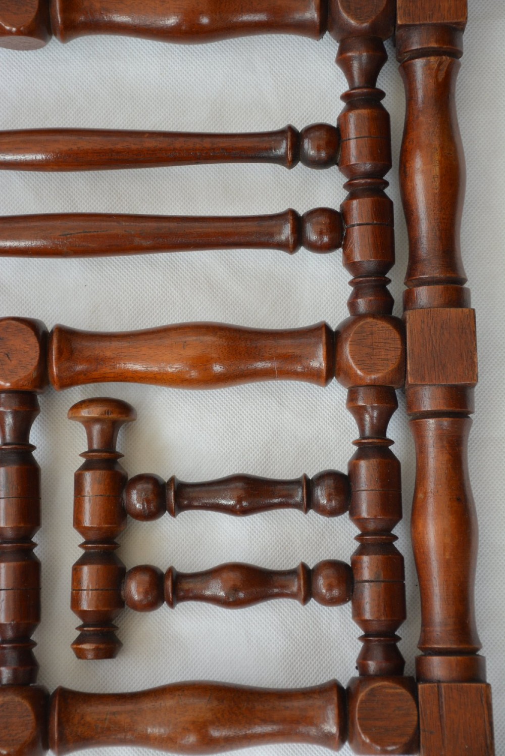 A wall-mounted dark wood coat rack constructed from turned spindles with multiple hanging pegs and decorative corner finials. View XIII