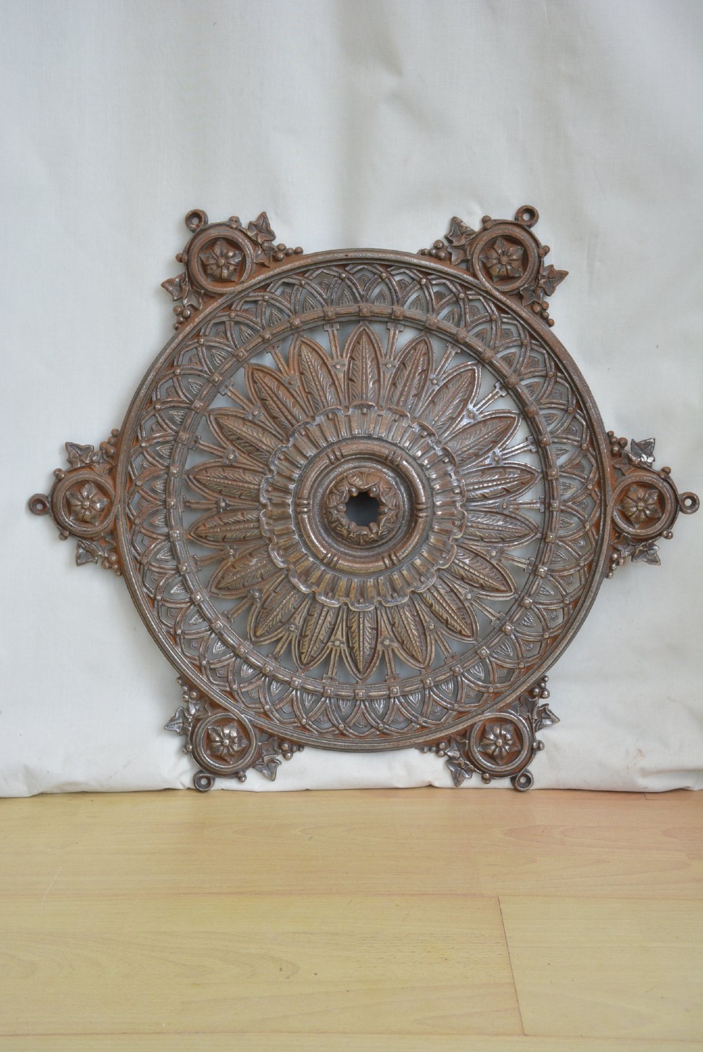 A circular Victorian cast iron ceiling rose featuring central feather relief detail surrounded by pierced openwork and ivy leaf border lugs. View IV