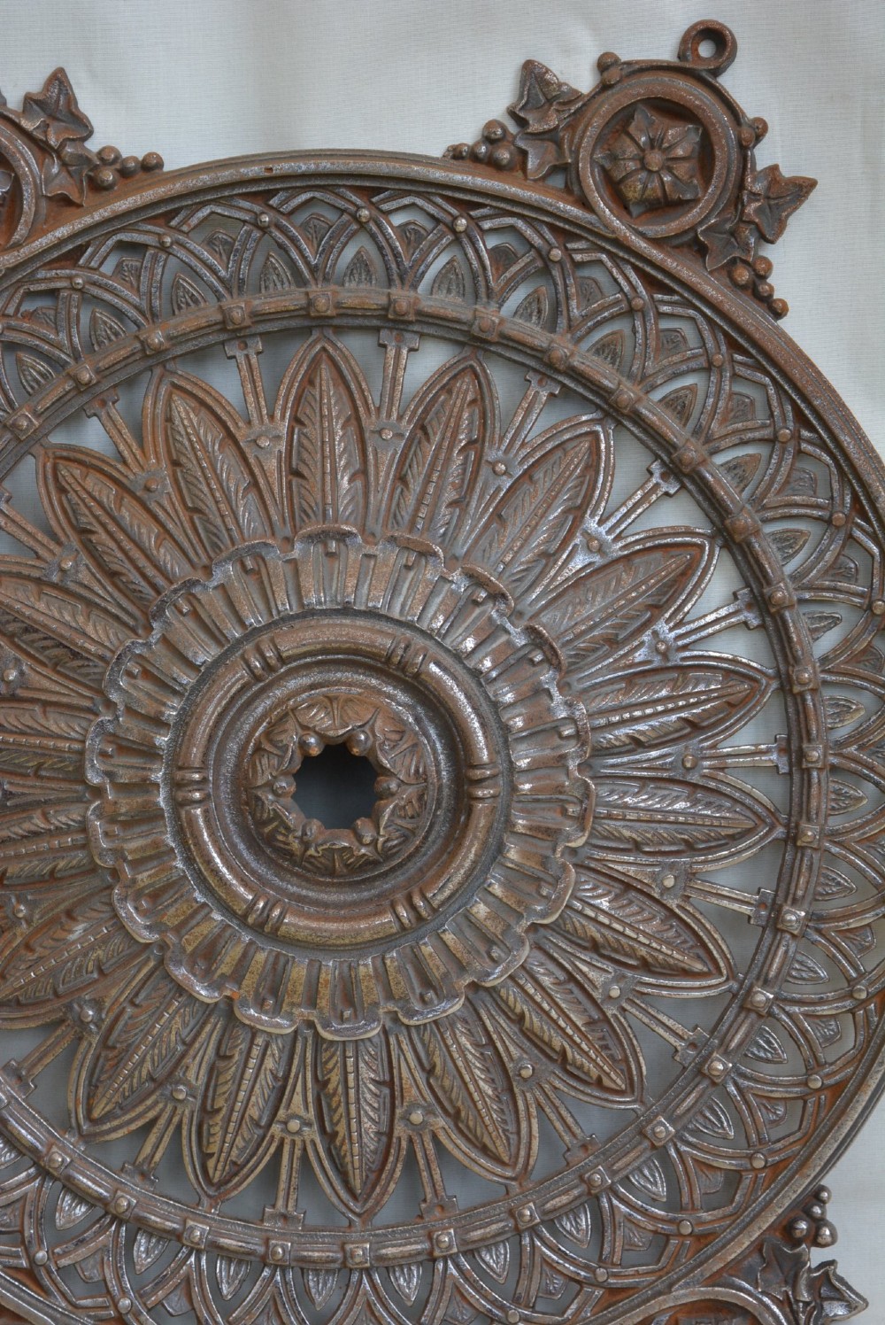 A circular Victorian cast iron ceiling rose featuring central feather relief detail surrounded by pierced openwork and ivy leaf border lugs. View VII