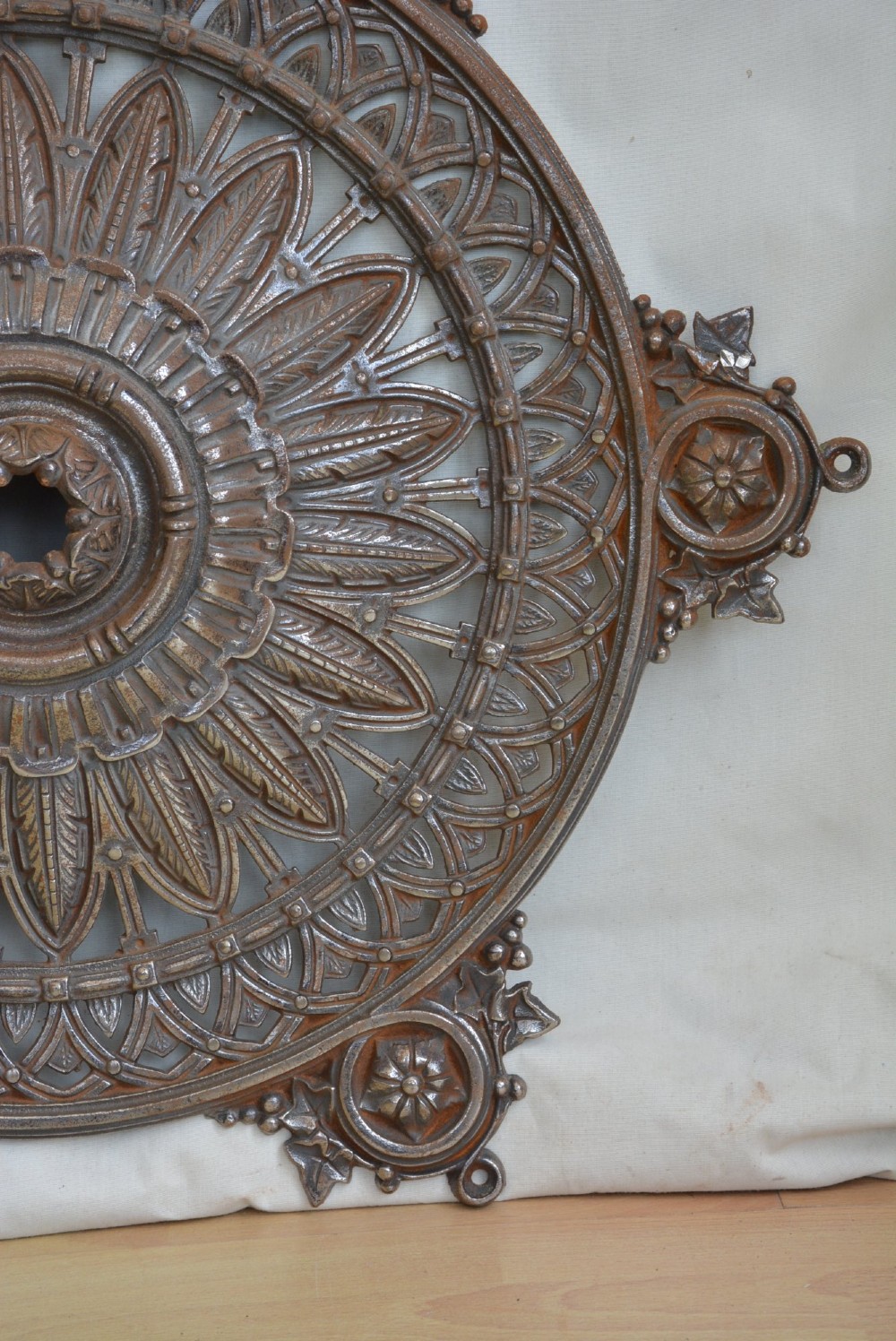A circular Victorian cast iron ceiling rose featuring central feather relief detail surrounded by pierced openwork and ivy leaf border lugs. View VIII