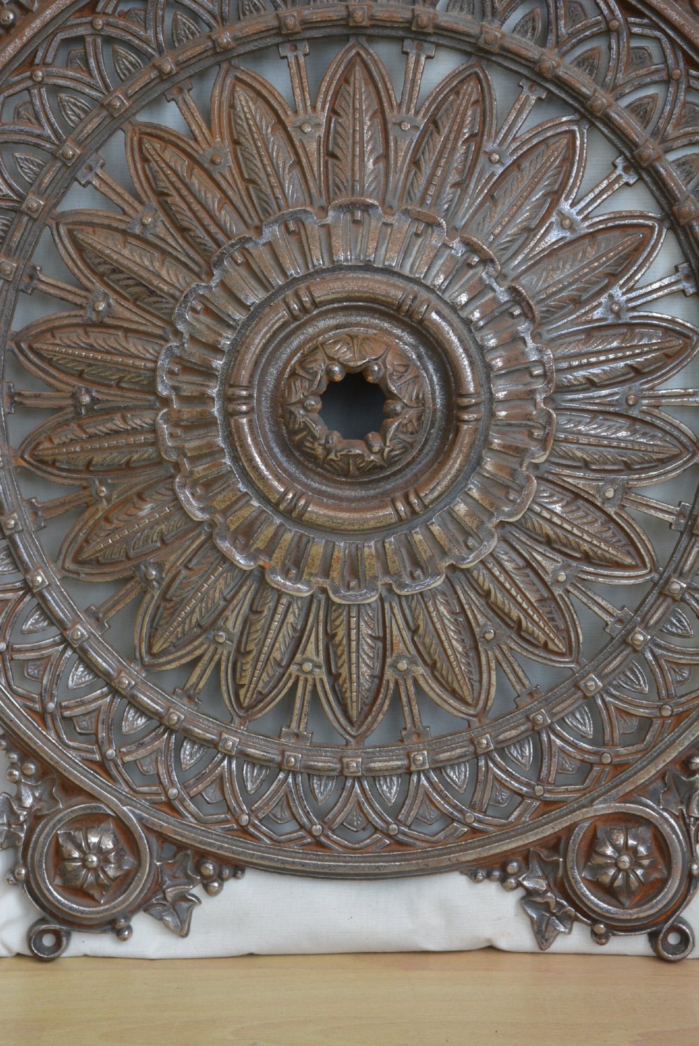 A circular Victorian cast iron ceiling rose featuring central feather relief detail surrounded by pierced openwork and ivy leaf border lugs. View IX