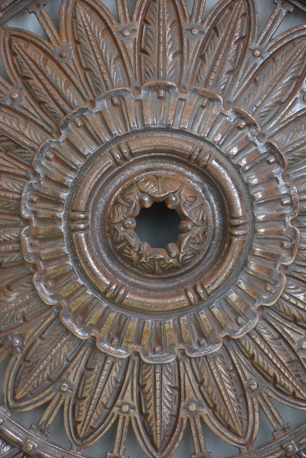 A circular Victorian cast iron ceiling rose featuring central feather relief detail surrounded by pierced openwork and ivy leaf border lugs. View X