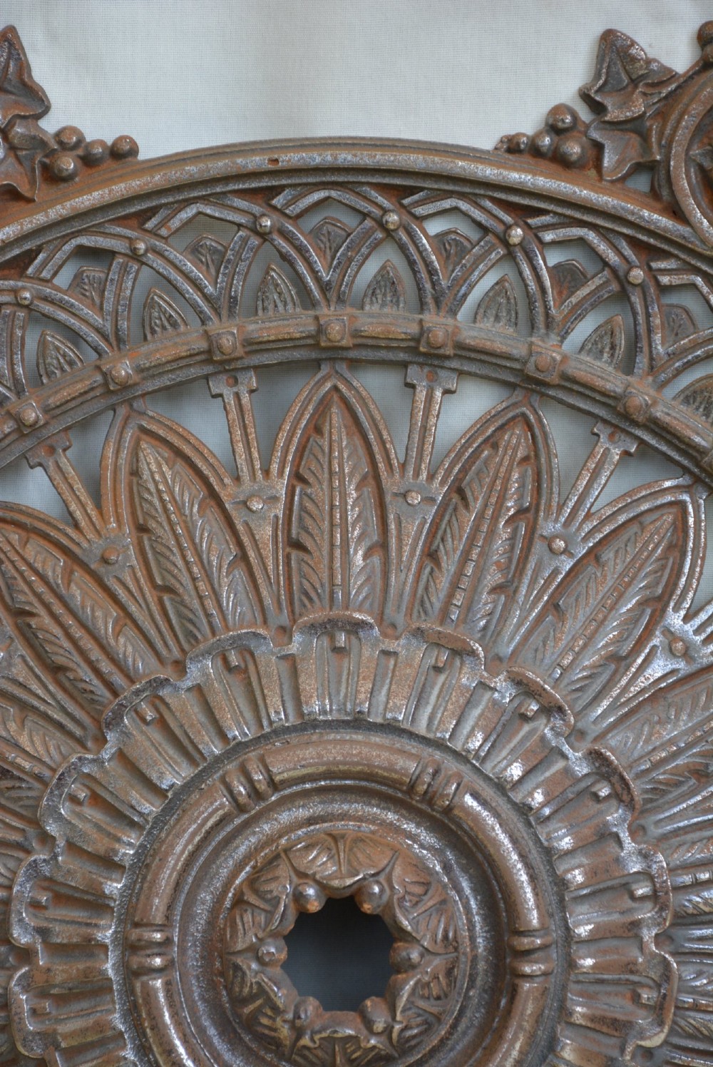 A circular Victorian cast iron ceiling rose featuring central feather relief detail surrounded by pierced openwork and ivy leaf border lugs. View XII