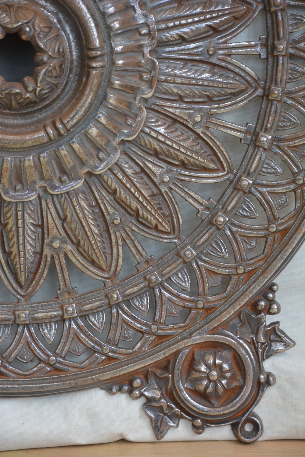 A circular Victorian cast iron ceiling rose featuring central feather relief detail surrounded by pierced openwork and ivy leaf border lugs. View XIV