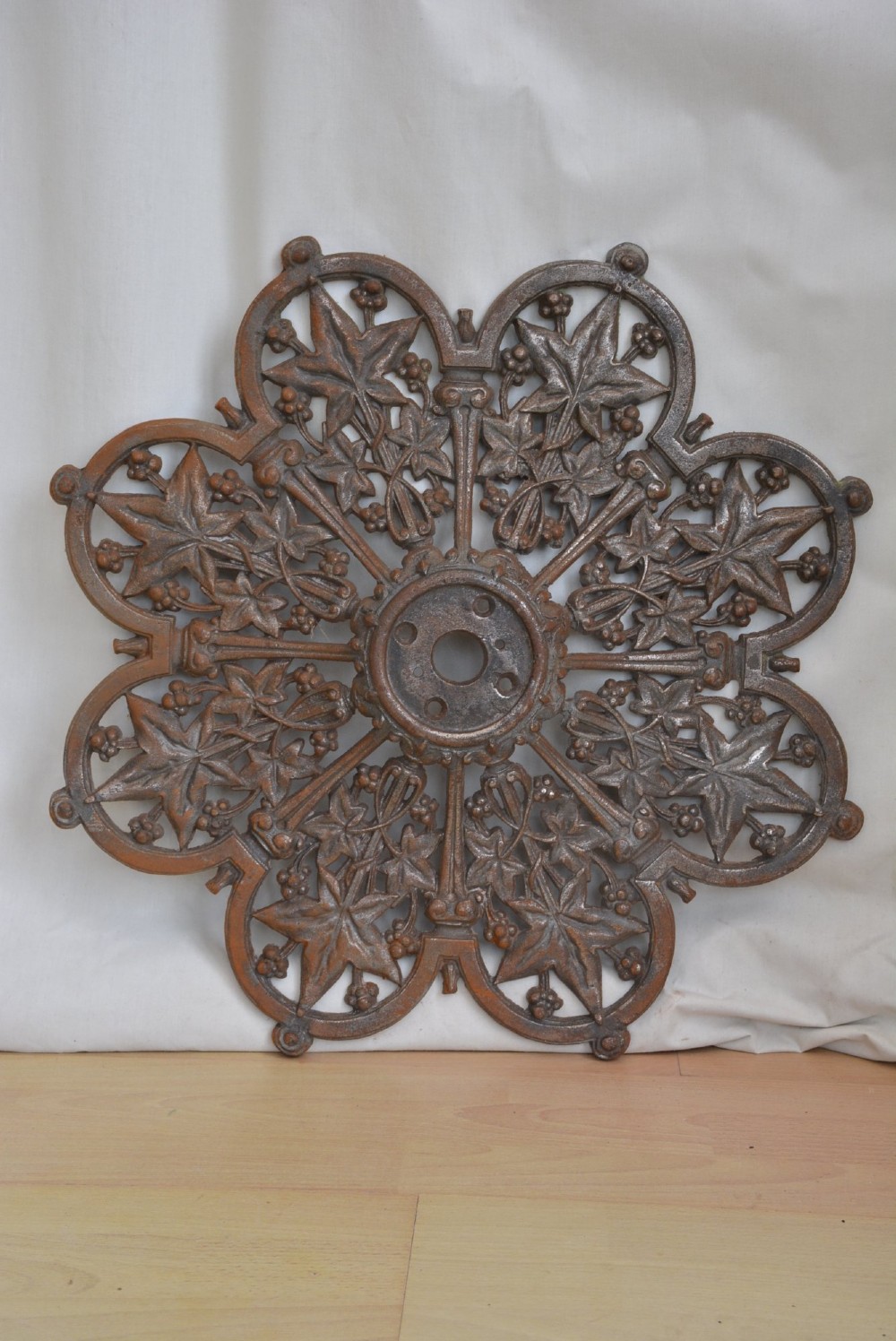 A circular Victorian cast iron ceiling rose featuring an openwork lobed design with raised ivy leaf and berry motifs surrounding a central circular aperture. View II