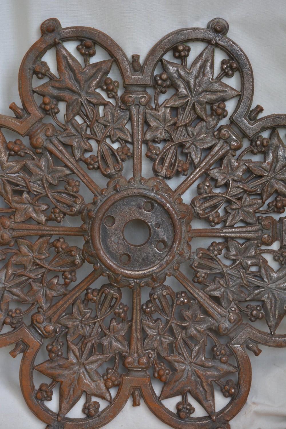 A circular Victorian cast iron ceiling rose featuring an openwork lobed design with raised ivy leaf and berry motifs surrounding a central circular aperture. View IV