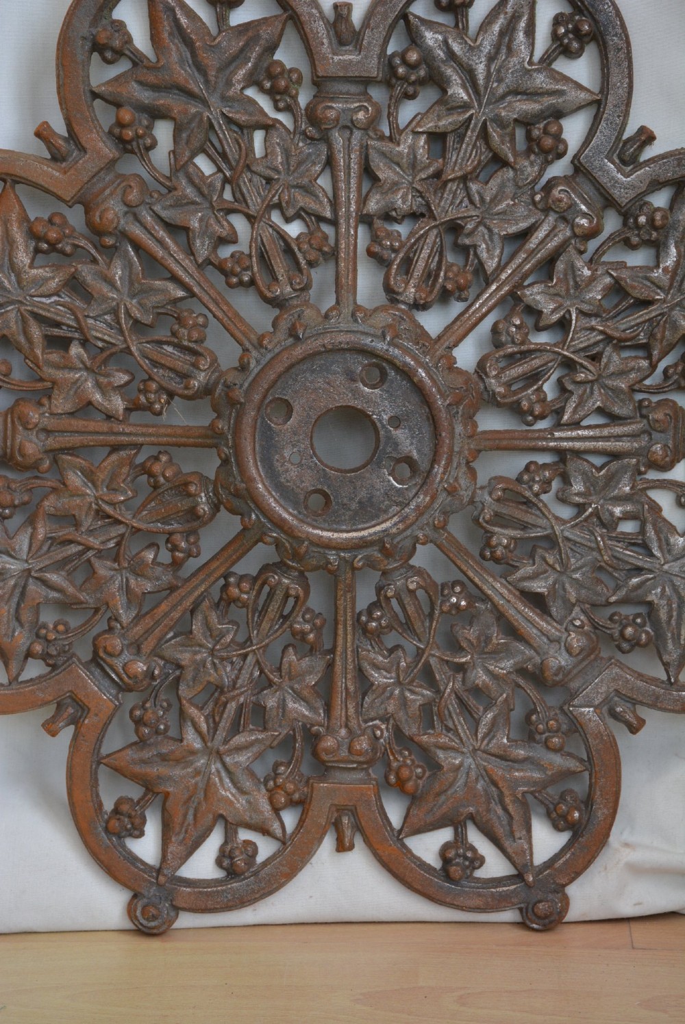 A circular Victorian cast iron ceiling rose featuring an openwork lobed design with raised ivy leaf and berry motifs surrounding a central circular aperture. View VI