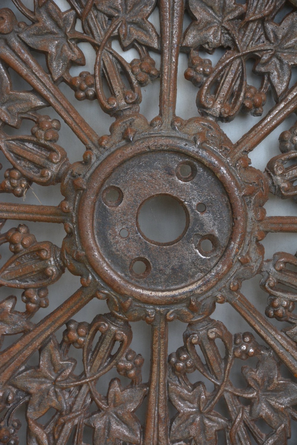 A circular Victorian cast iron ceiling rose featuring an openwork lobed design with raised ivy leaf and berry motifs surrounding a central circular aperture. View VII