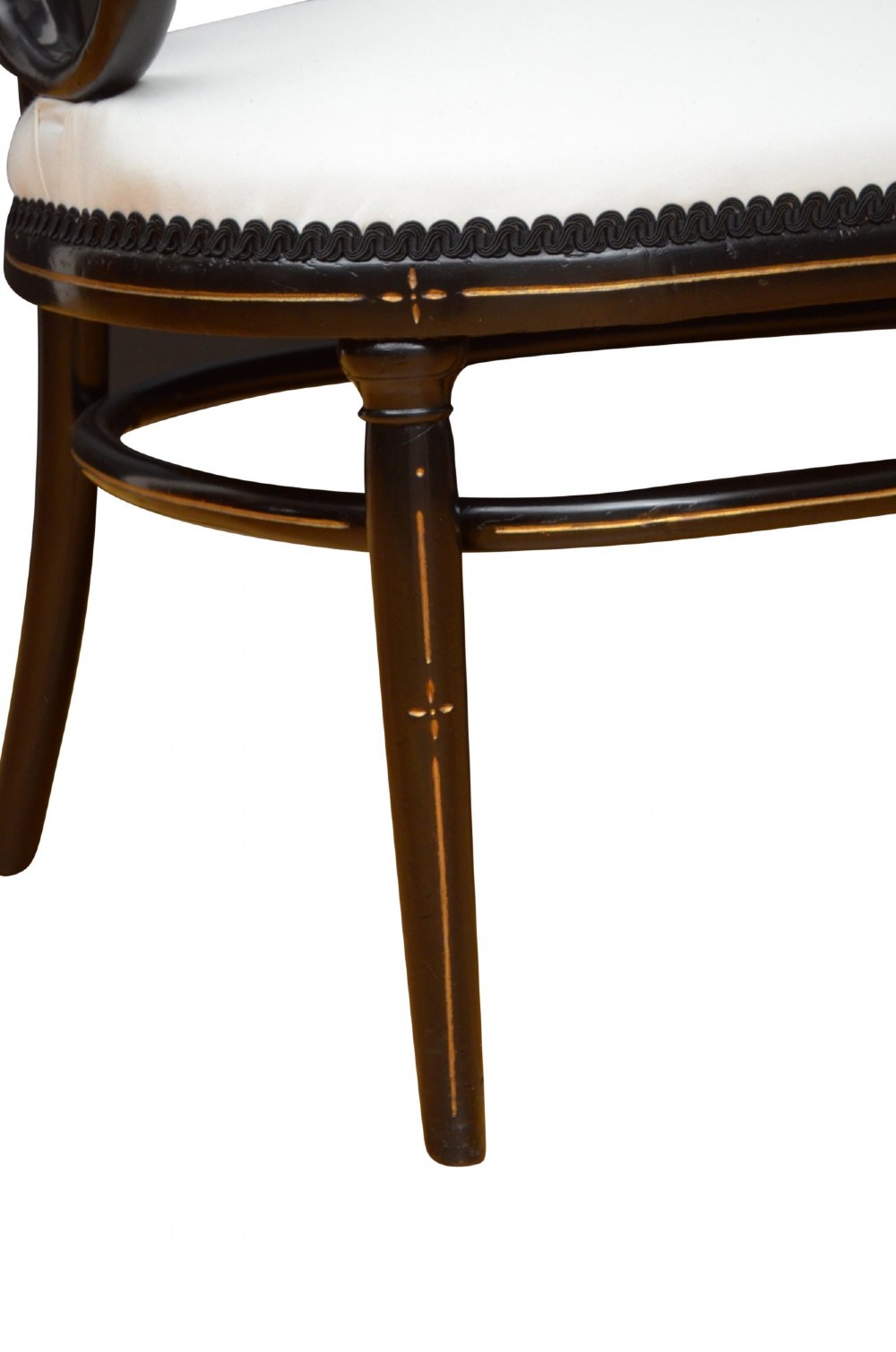 An ebonised bentwood armchair featuring white upholstered seat and back panels, scrolled armrests, and gold linear detailing on a black wooden frame. View X