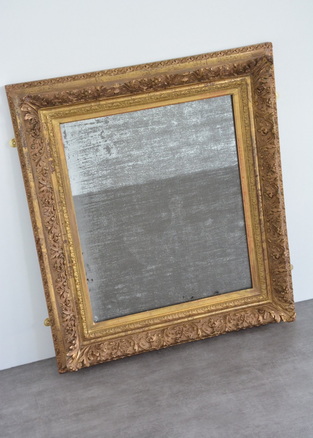 A rectangular antique wall mirror featuring a heavily carved gold giltwood frame and a foxed mirror glass plate. View XIII